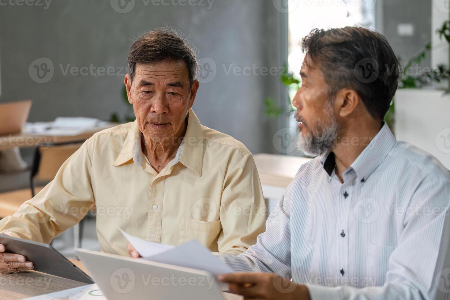 Businessmen discussing financial strategies in a modern office setting with focus on senior and mid-aged professionals photo