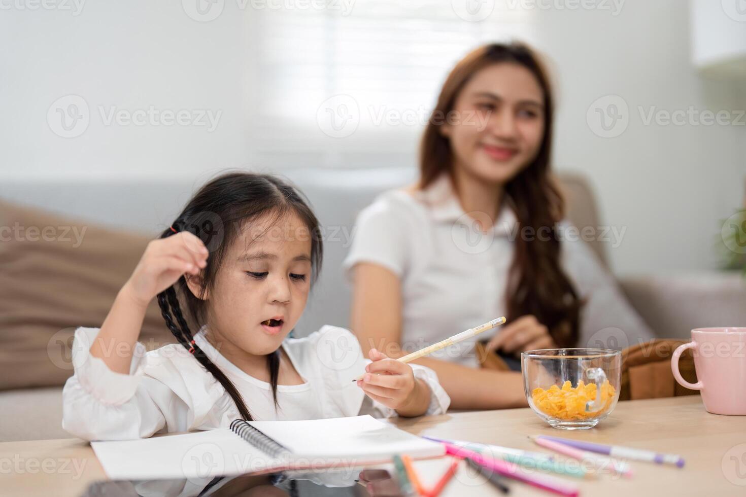 Learning and Fun Moments. A child focuses on her drawings while her mother joyfully observes, encouraging artistic expression. photo