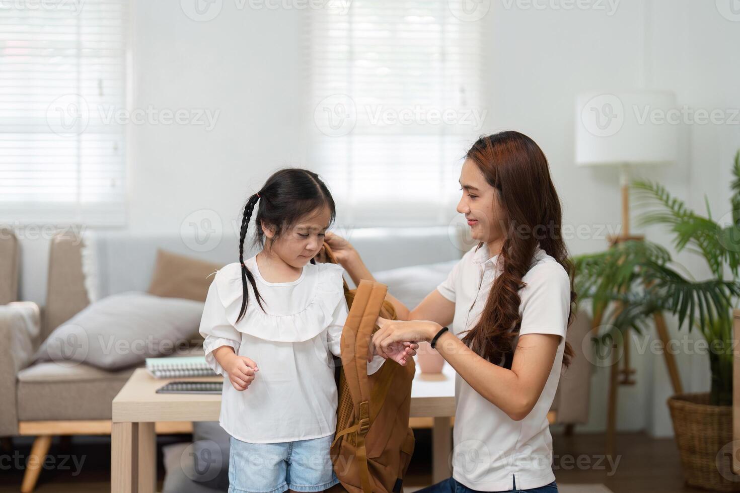 Encouraging Confidence in the School Journey. A mother helps her daughter dress while preparing for school. photo