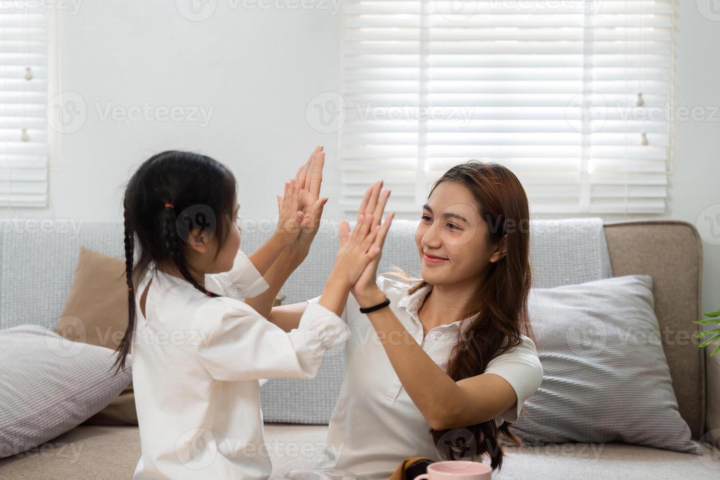Playful Interaction and Bonding. A mother and daughter playing a hand game at home, fostering joy and connection. photo