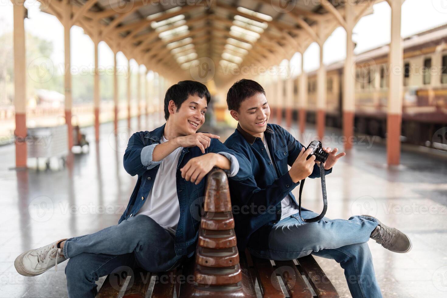 Travel and Friendship. Two friends enjoying a playful moment at a train station, capturing memories with a camera. photo