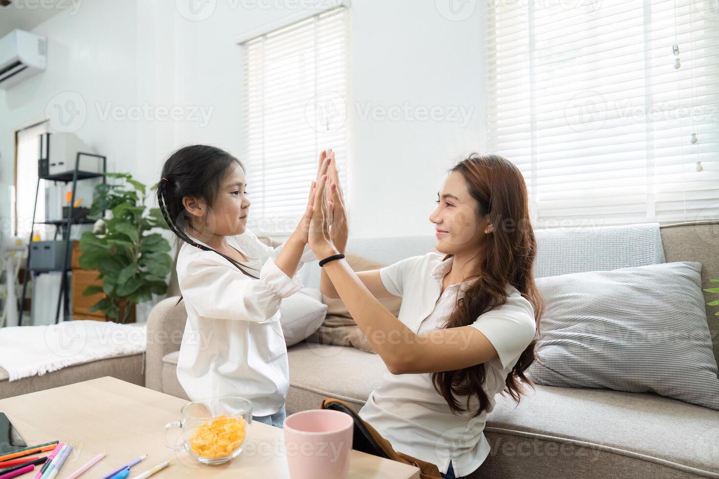 Playful Interaction and Connection. A girl and her mother engaging in a fun high-five moment. photo