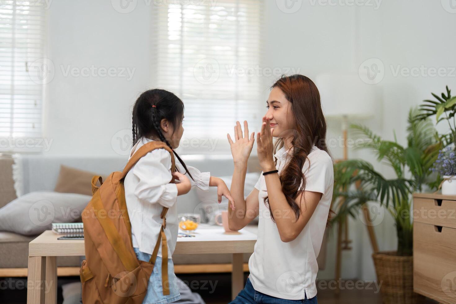 Back to School and Playful Goodbyes. A mother playfully waves goodbye to her daughter as she prepares for school. photo