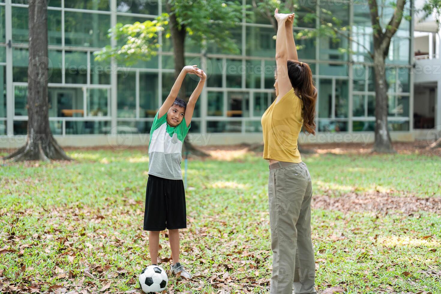 Warm-up and Playfulness. A woman and a young boy stretching and enjoying their time in the park. photo