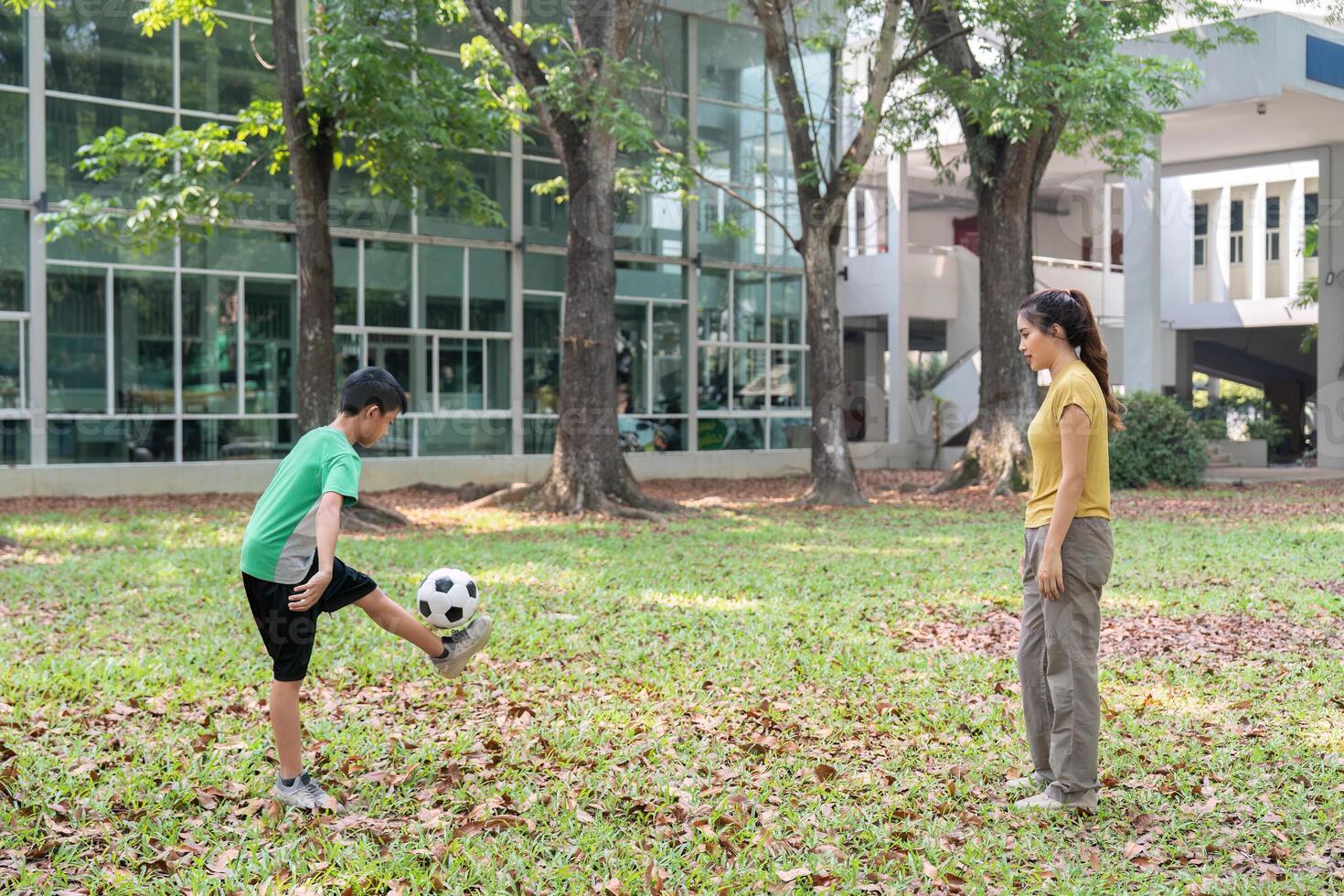Practice and Play in Nature. A young boy practices soccer skills in a park while his mother watches with encouragement. photo