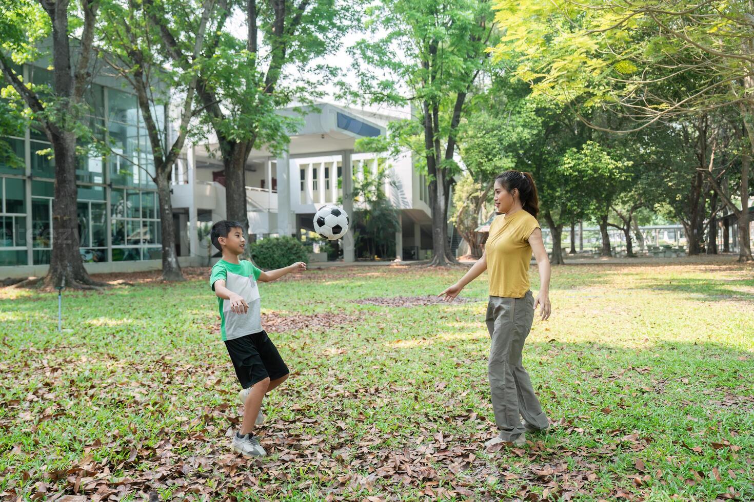 Active Play and Joyful Moments. A woman enjoying soccer with a boy in an outdoor park. photo