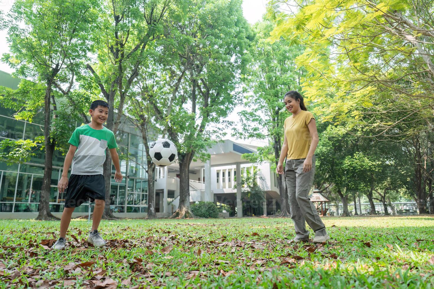 Soccer Skills and Family Bonding. A woman and boy practicing soccer in a lively park. photo