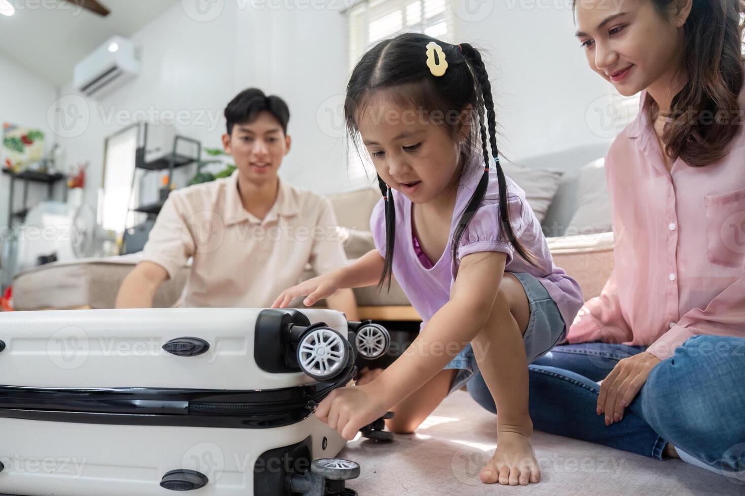 Childhood Discovery and Family Interaction. A little girl plays with a suitcase beside her parents. photo