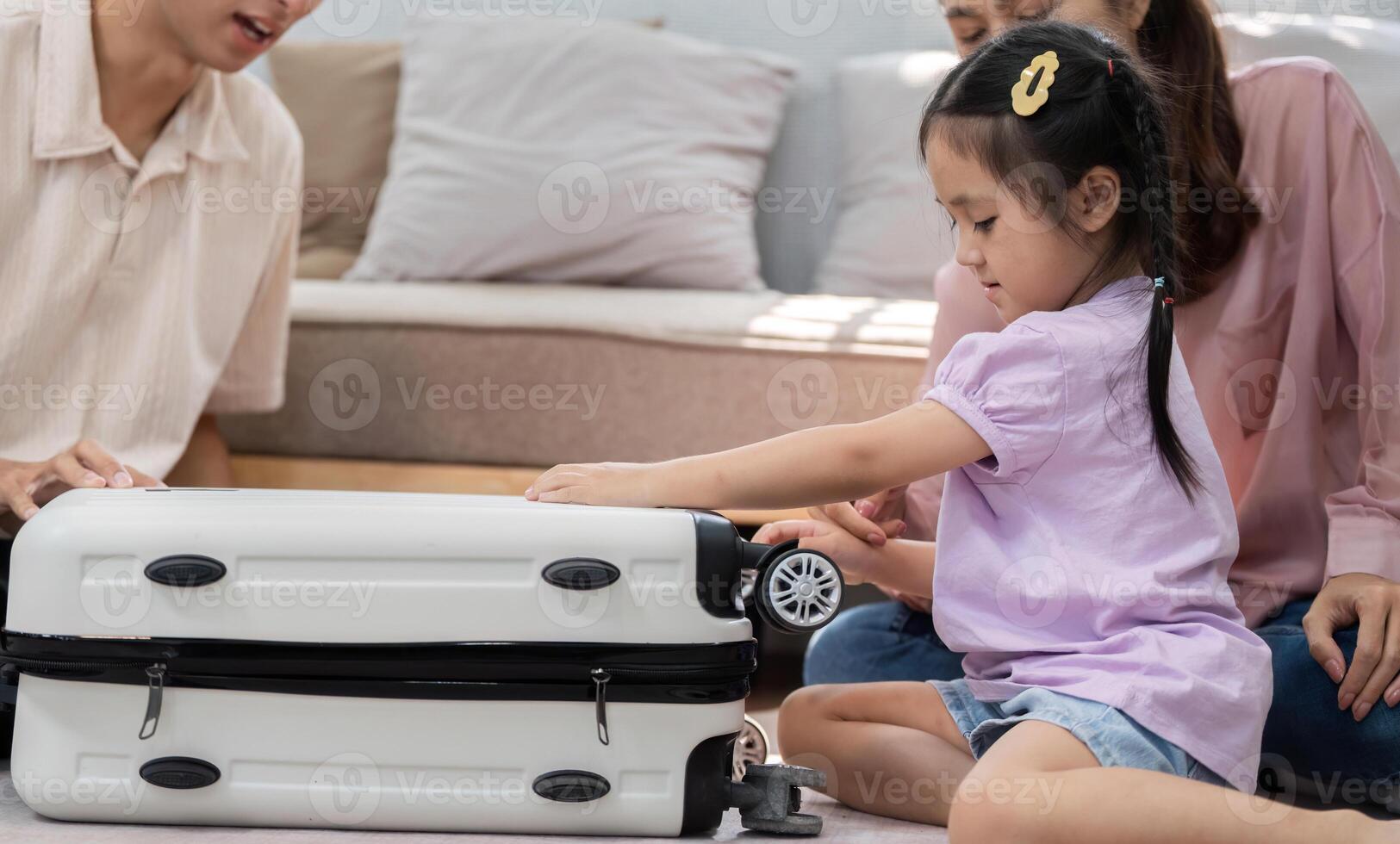 Family Fun and Interaction. A child happily exploring a suitcase with her parents nearby. photo