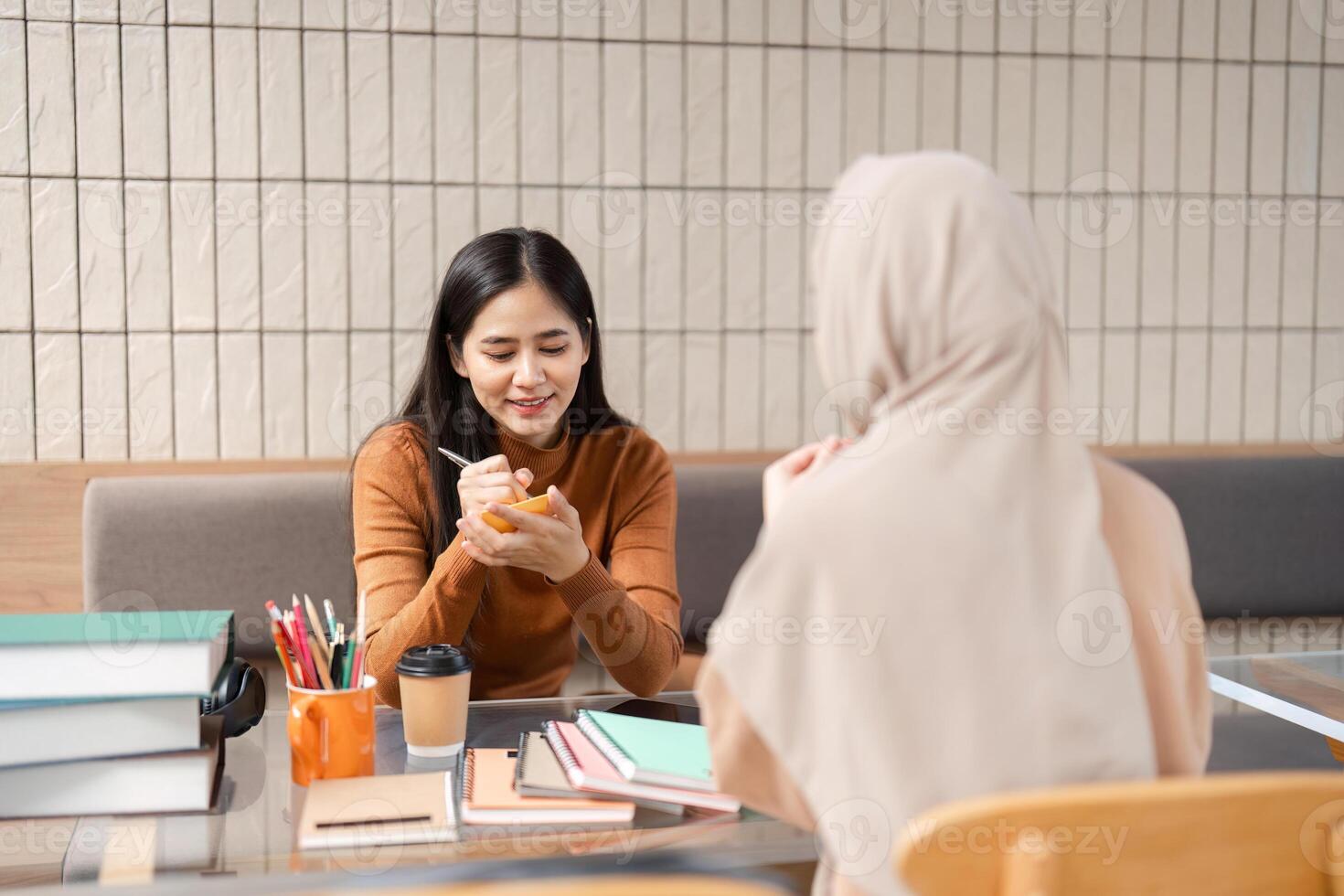 In-Depth Discussion and Study. Two women engaged in focused conversation over study materials. photo
