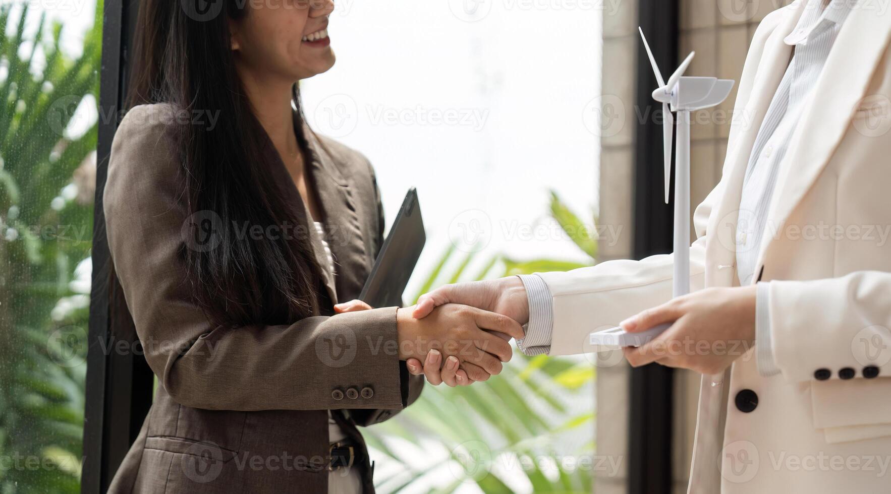 Professional Networking and ESG. Businesswomen shaking hands over sustainable practices in an office environment. photo