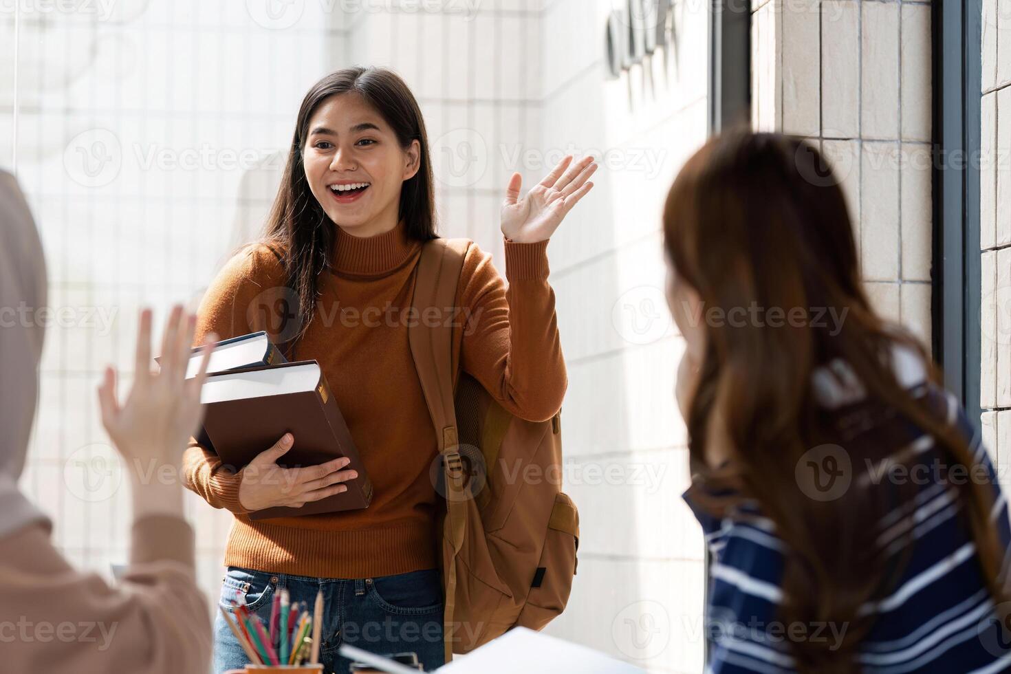 Student Arrival and Greeting. A student enters a cafe, greeting friends with enthusiasm and books in hand. photo
