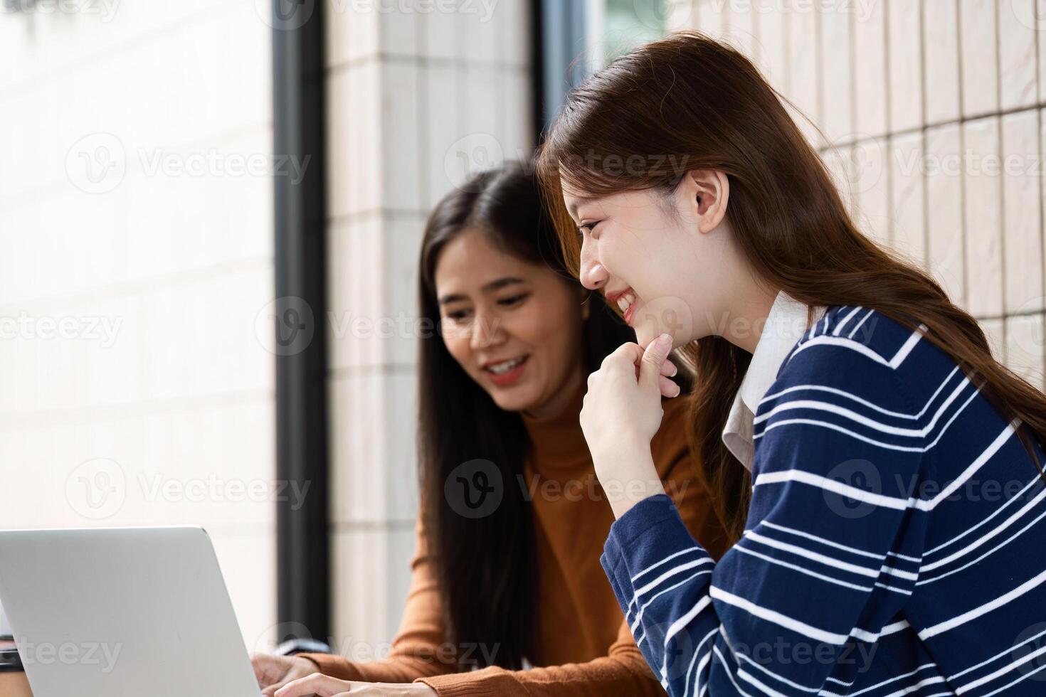 Digital Learning and Collaboration. Two students enjoy digital resources while studying together at a cafe. photo