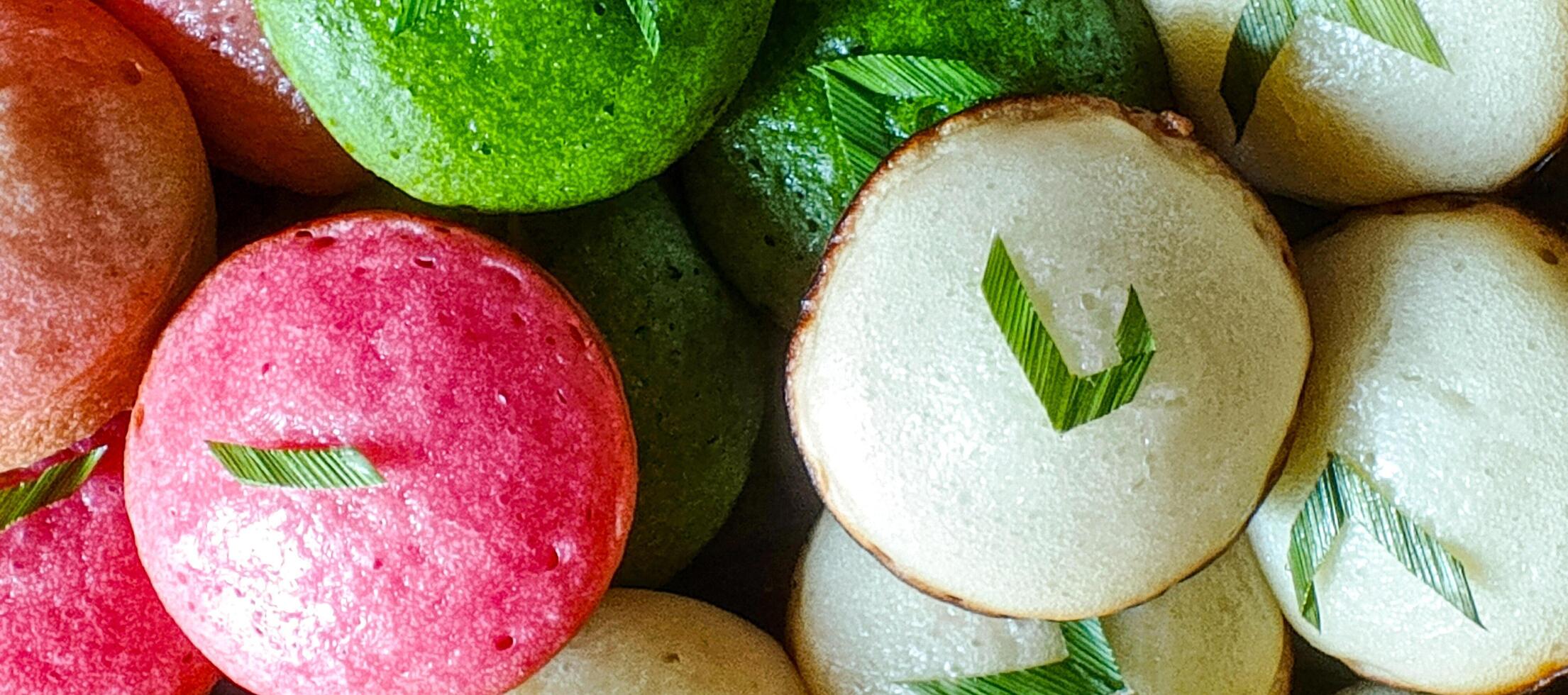Close-up of traditional Indonesian apem, soft and fluffy steamed rice cakes in red, green, and white, decorated with pandan leaves for an authentic touch. photo