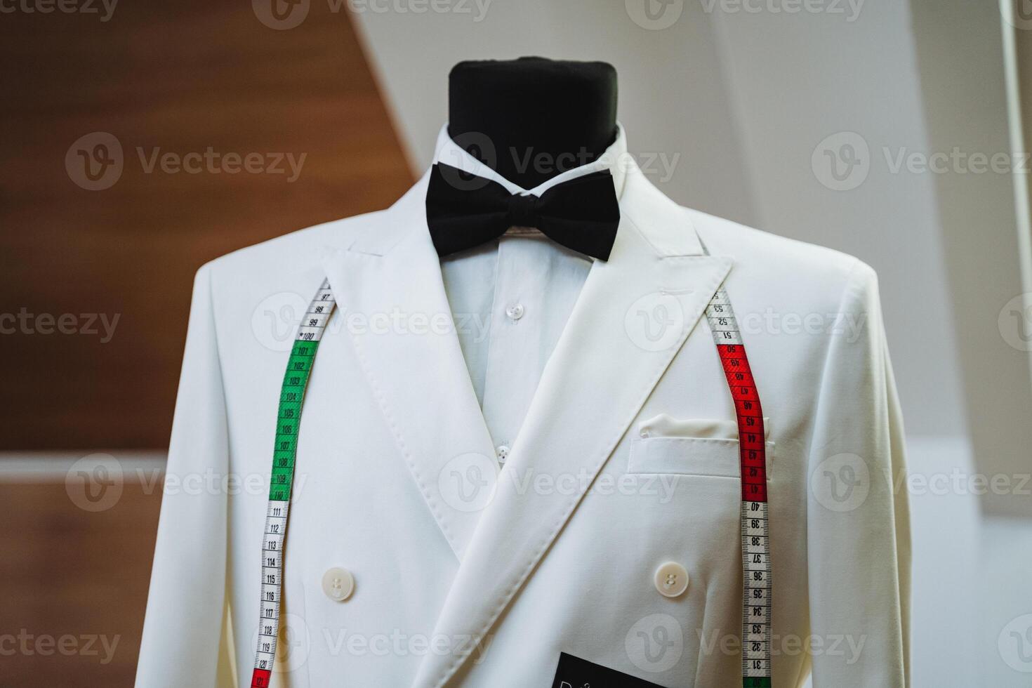 A stylish white suit with a classic black bow tie is elegantly displayed on a mannequin, showcasing a sophisticated fashion sense that stands out and captures attention effortlessly photo