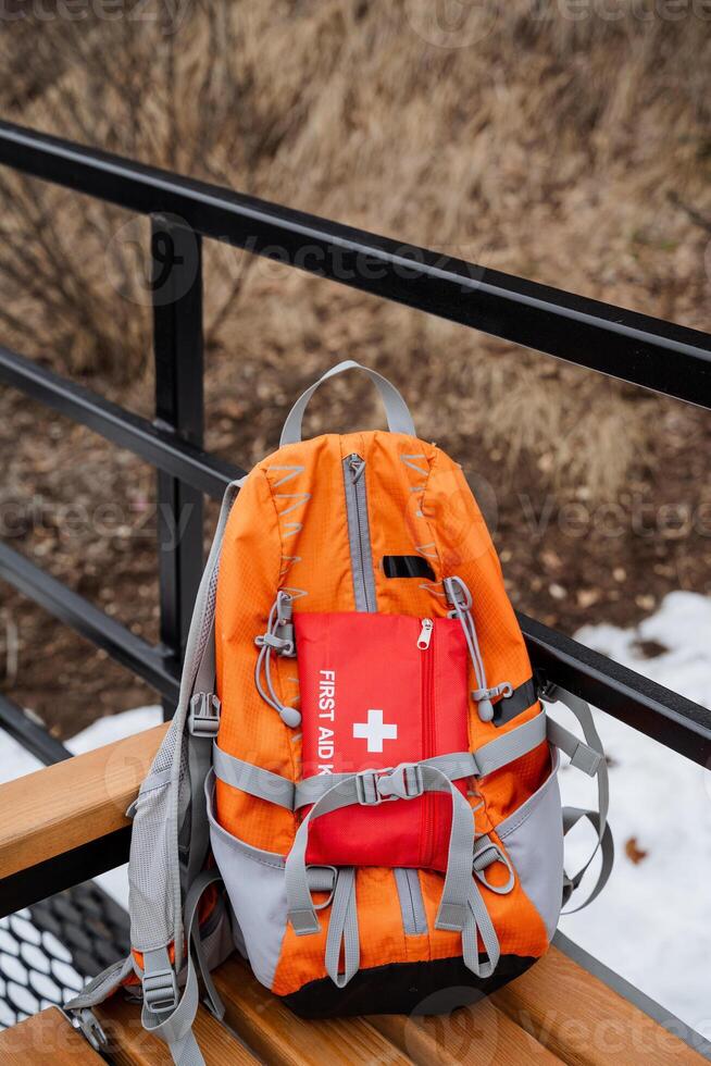 A wellprepared backpack equipped with a comprehensive first aid kit is currently resting on a sturdy wooden bench, ready for any outdoor adventure or emergency situation photo