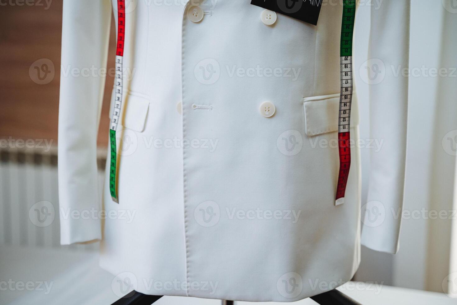A pristine white coat elegantly displayed on a mannequin, adorned with a measuring tape, serves to emphasize the crucial significance of precise measurements in the world of fashion design photo