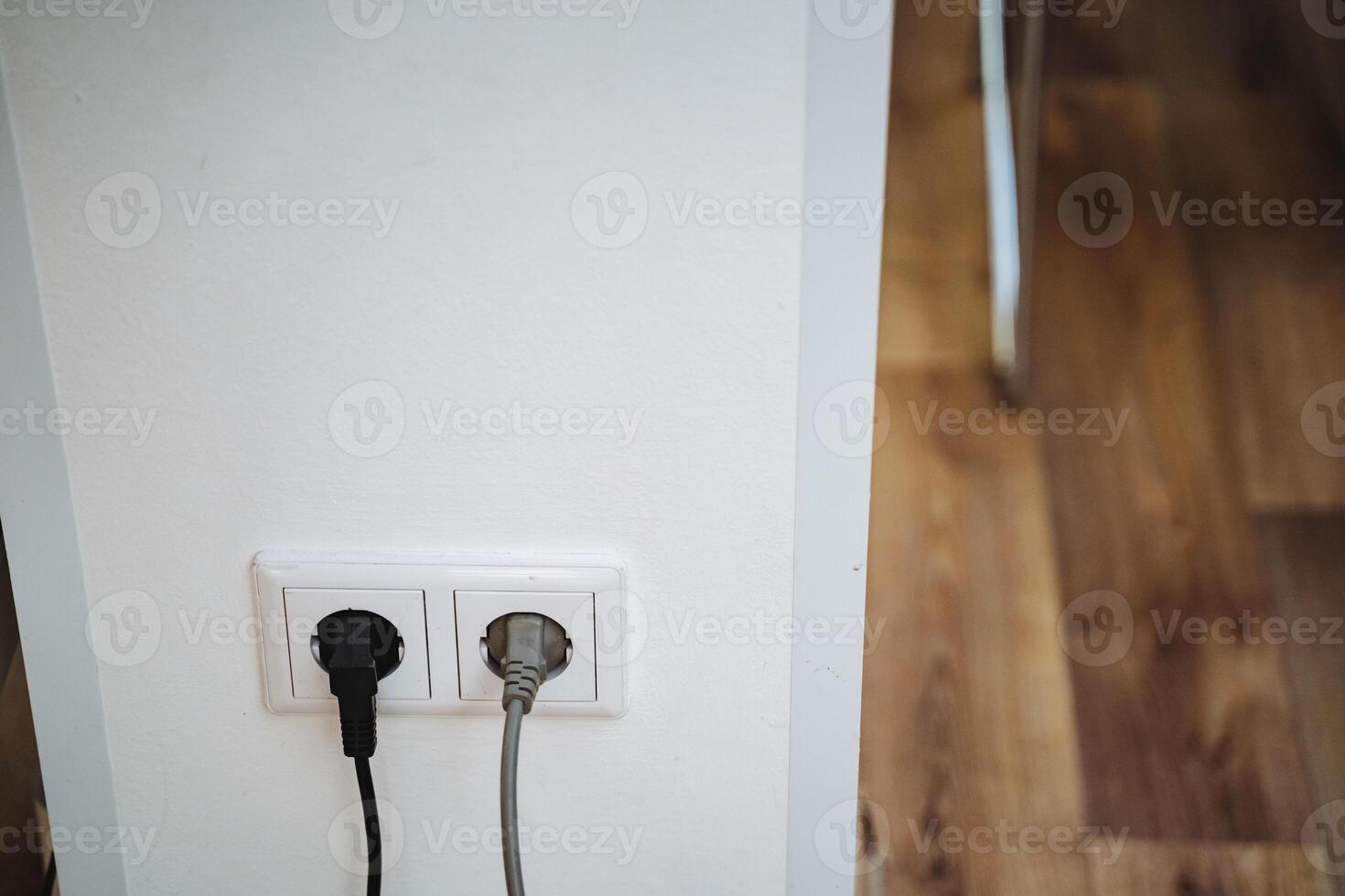 Two electrical plugs are currently inserted into a wall socket, enabling power supply to devices or appliances connected to them for functionality and use in technology applications photo