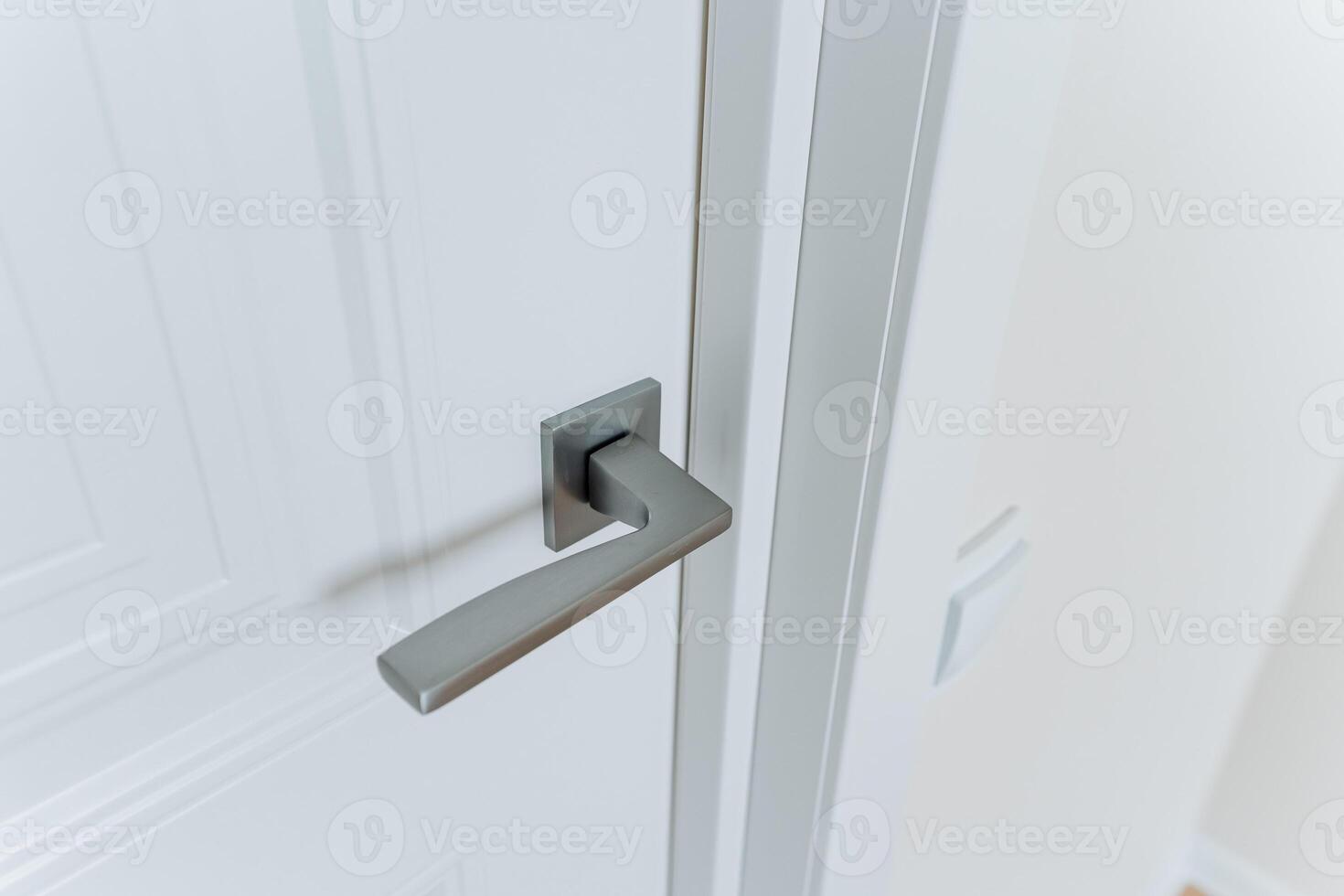 A CloseUp View of a Contemporary Modern Door Handle Installed on a White Painted Door, Set Against a Bright Interior Environment, Showcasing Its Elegance and Design Features photo