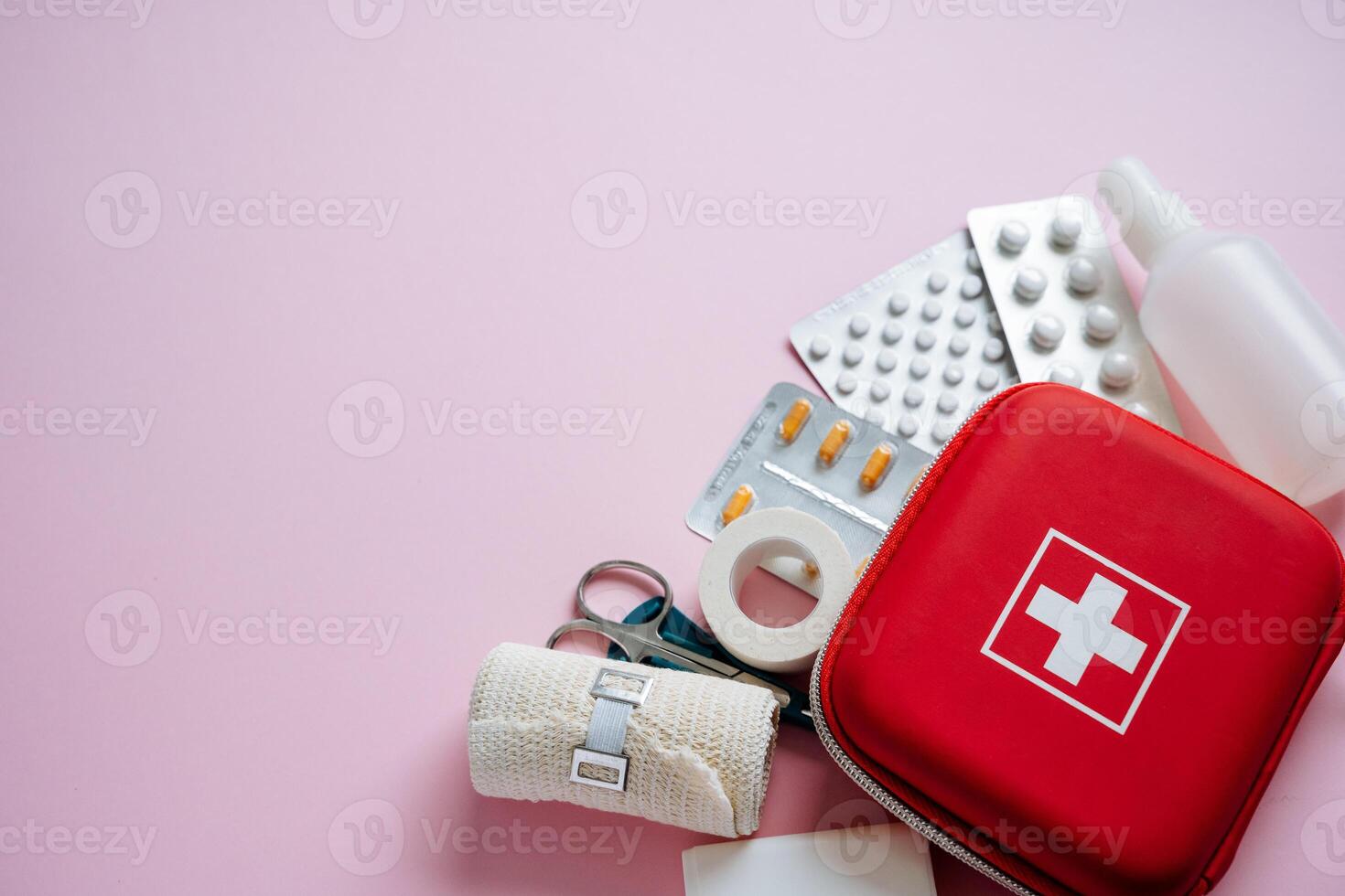 An Essential First Aid Kit featuring various Medical Supplies, all displayed on a soft pink background, perfect for health and safety preparedness at all times photo
