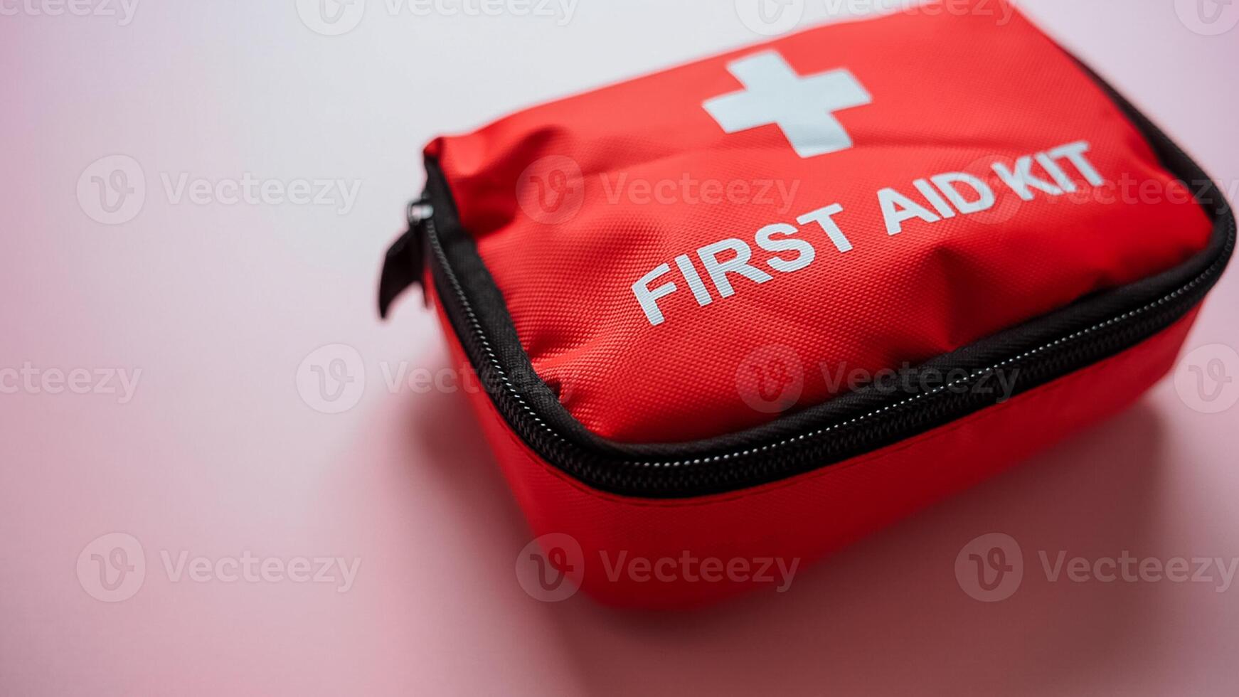A bright red first aid kit is currently positioned on a soft pink surface, ready for any potential emergencies that may arise, providing essential health care support whenever needed photo