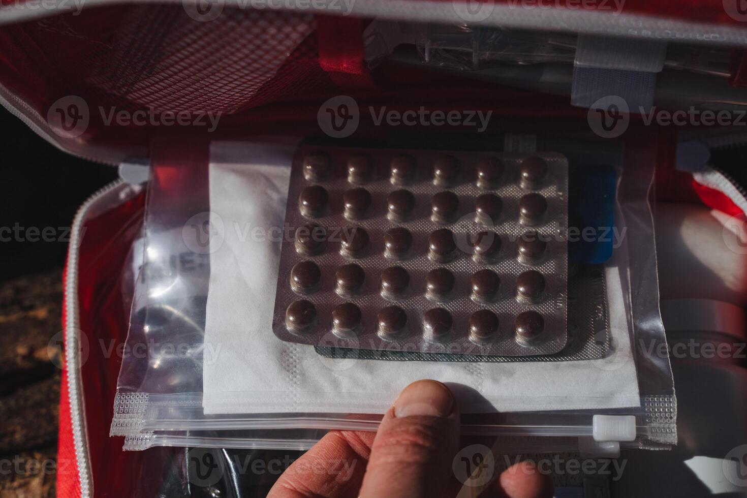 A person is holding a blister pack containing several pills in their hand, which is made of plastic and often comes in a small box that can be stored or carried as baggage photo