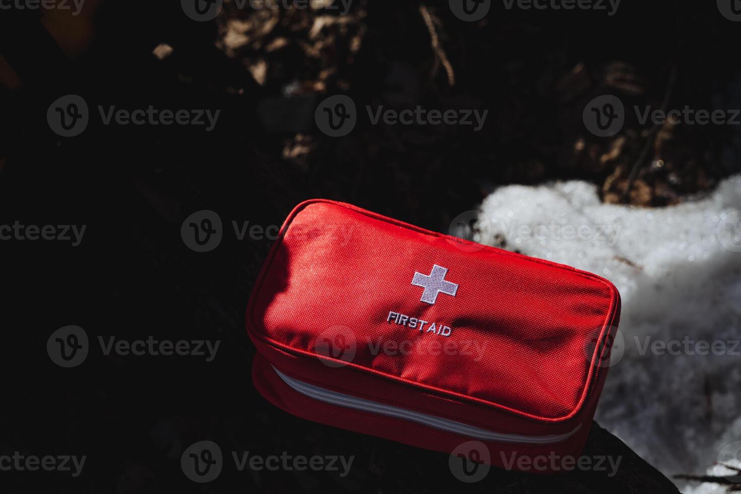 A bright red first aid kit is sitting prominently on top of a substantial pile of soft, white snow, ready to provide necessary medical assistance when needed in cold weather conditions photo