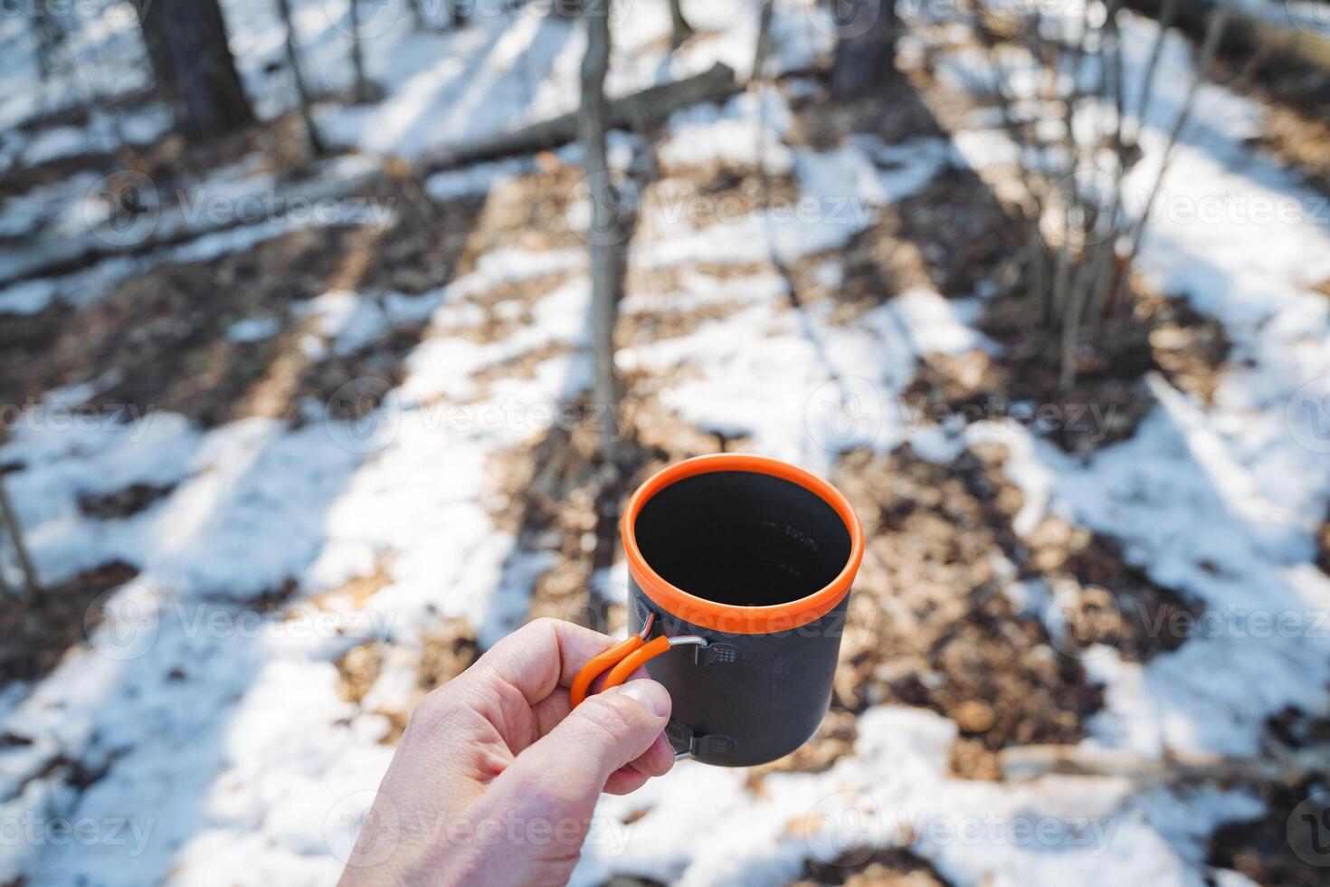 A person is standing outside in the beautiful snow while holding a warm cup of delicious coffee, creating a comforting and cozy contrast against the chilly winter landscape surrounding them photo