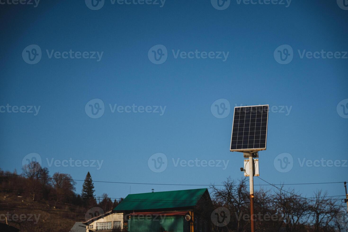 There is a quaint little house that features a charming green roof, along with a solar panel strategically placed in front of it, harnessing energy from the sun for sustainable power photo