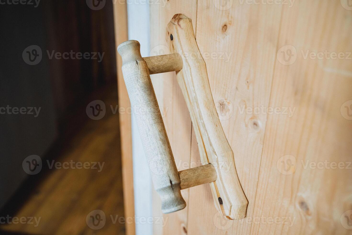 This is a beautifully crafted wooden door handle, showcased with a detailed closeup view, elegantly set against the robust and sturdy backdrop of a wellmade wooden door photo