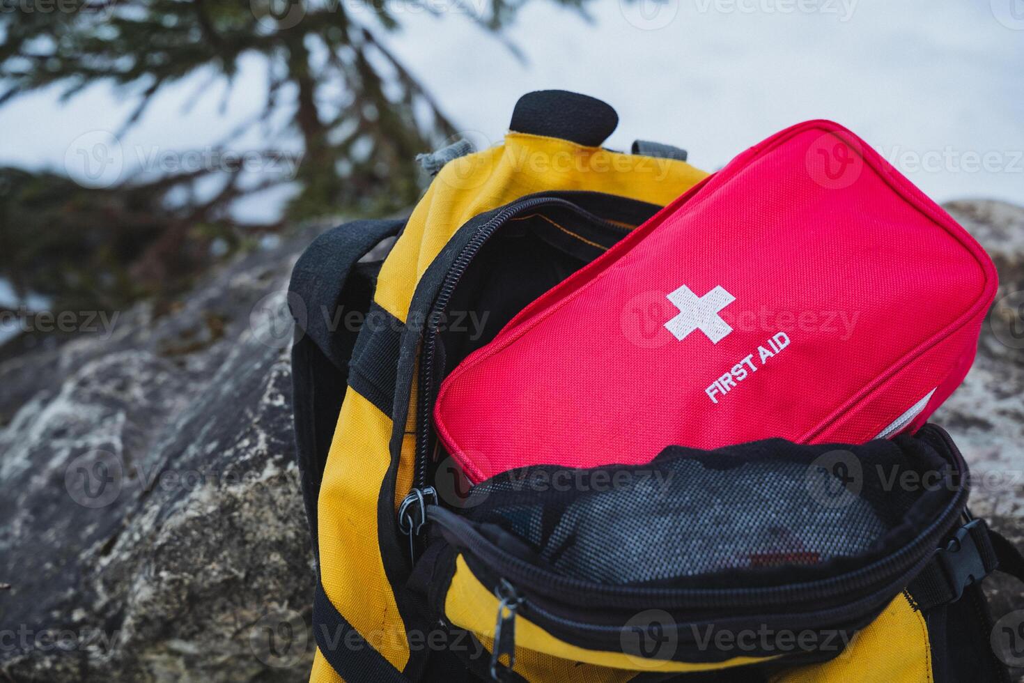 A vibrant yellow backpack is filled with essential items for various needs, including a bright red first aid kit that ensures easy and quick access during emergencies or outdoor activities photo