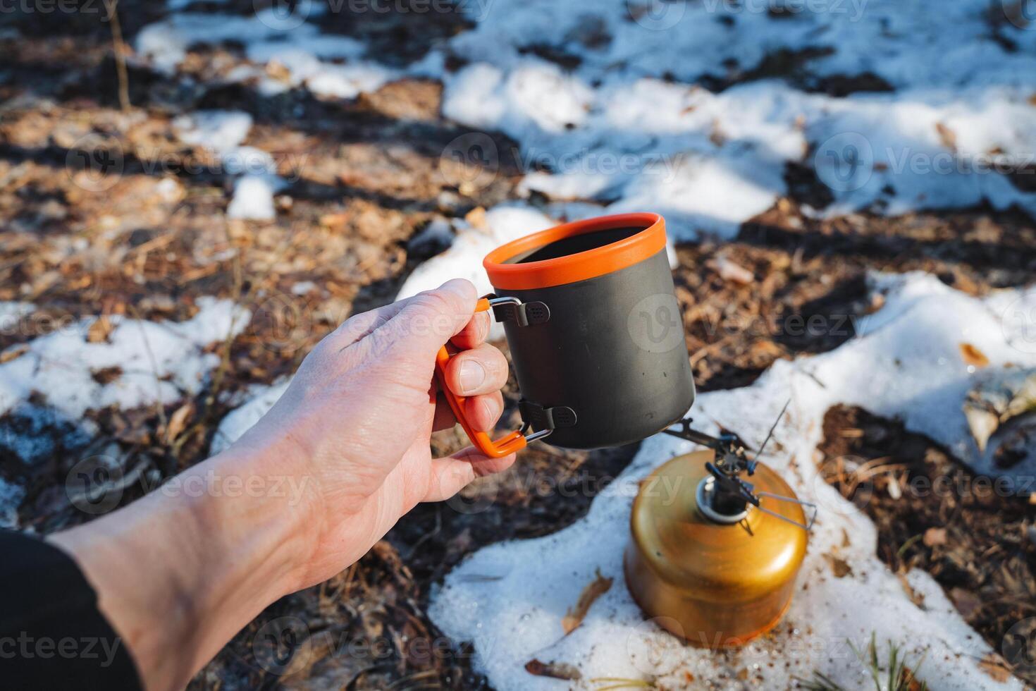 A person is standing outside in the snow, holding a warm cup of coffee in their hands, enjoying the chilly scenery while sipping on their drink. It is quite a lovely sight photo