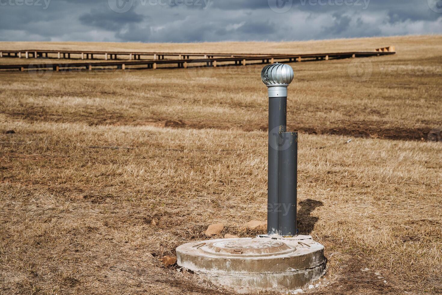 In the center of a wide, expansive open field stands a solitary pole, and towering in the background is a bridge that elegantly spans the distance, creating a truly striking visual scene photo