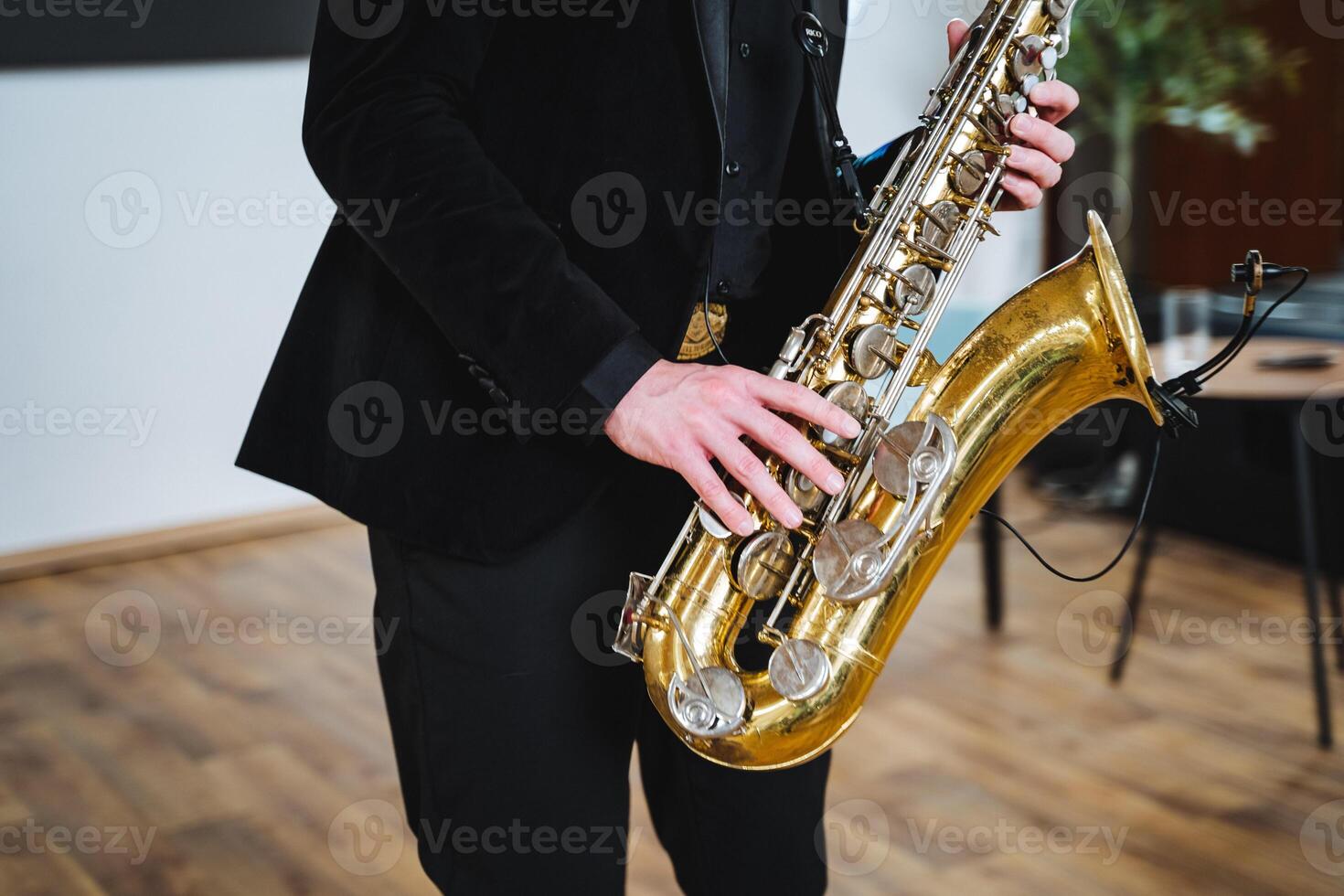 In a cozy, warmly lit room, a sophisticated man in a tailored suit passionately plays the saxophone, showcasing his talent and love for music that captivates all who hear it photo