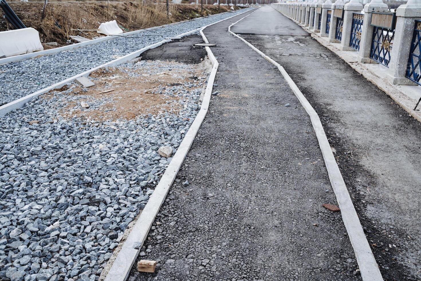 There is a road that features a distinctly marked white line running down the center, with a layer of gravel lining the sides, providing a clear demarcation for travelers photo