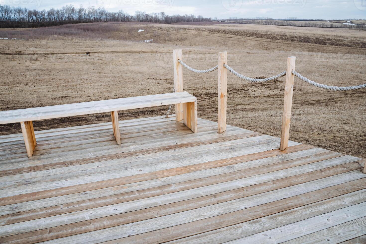 A beautifully crafted wooden deck featuring a sturdy bench and a charming rope fence, perfect for outdoor relaxation or entertainment, enhancing the gardens aesthetic appeal photo
