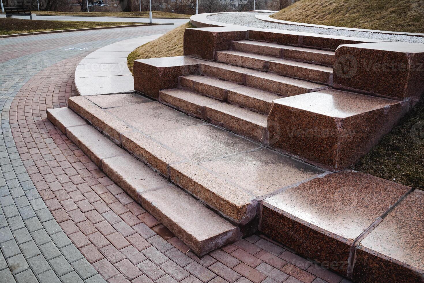 A beautiful set of stairs constructed from stone and bricks, elegantly placed on a wellmaintained sidewalk for pedestrians to use and enjoy while walking along their route photo