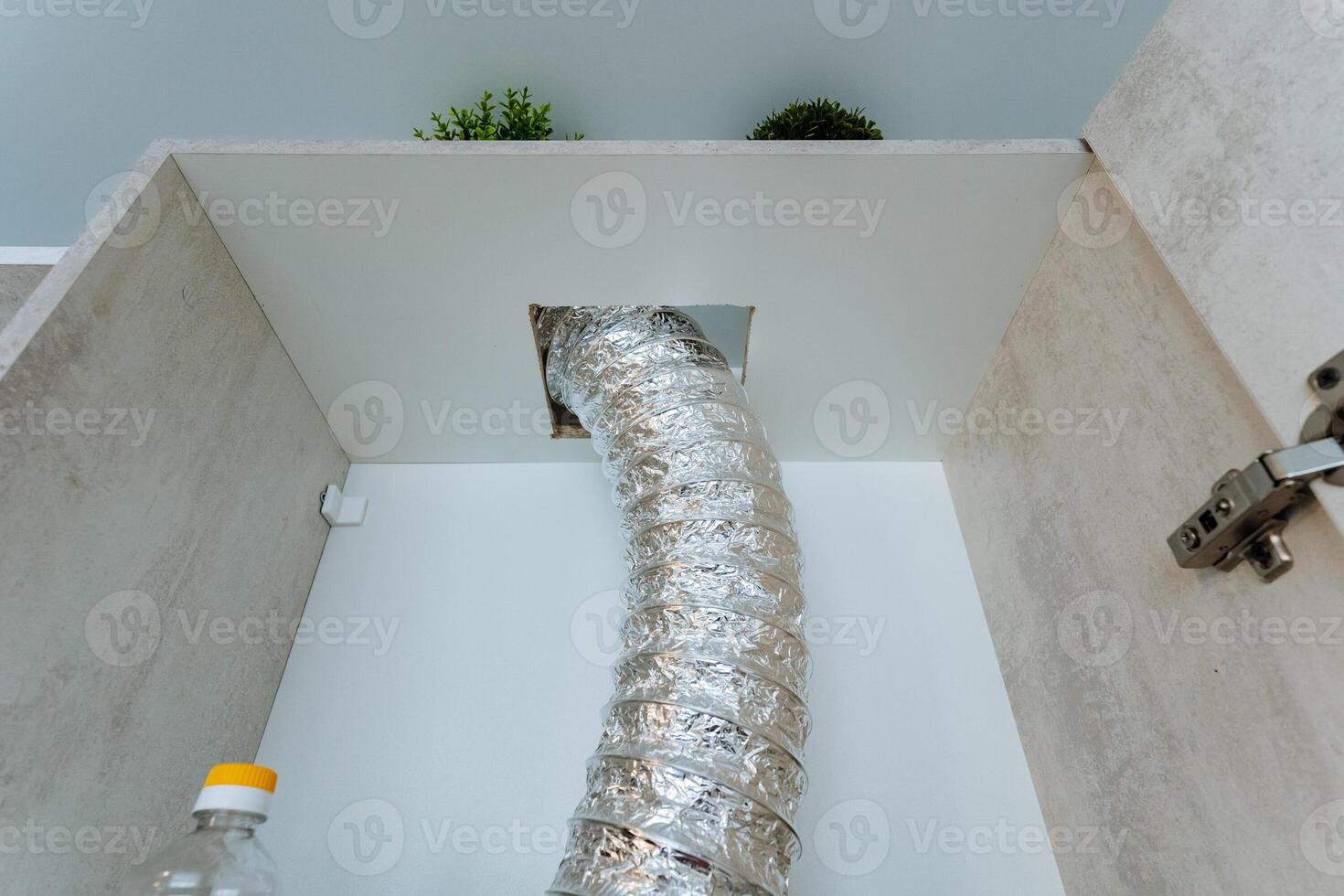A long hose is protruding from an opening that is situated in the wall of a cabinet, and this might be associated with plumbing functions or another sort of essential utility setup photo