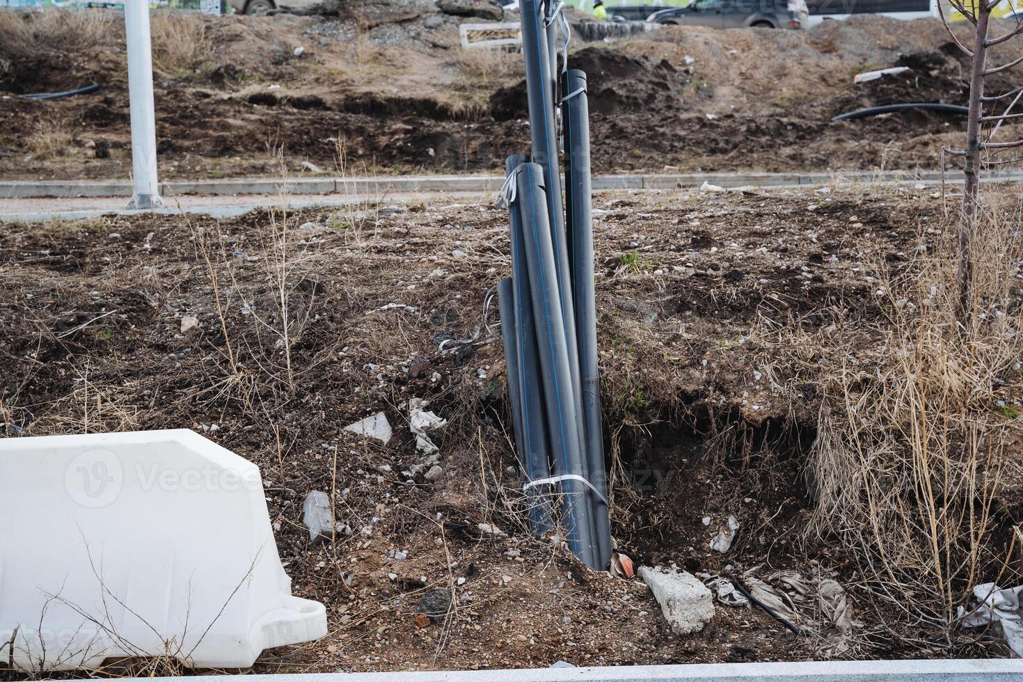 A significant number of pipes can be observed lying in the dirt beside a white barrier that separates the area, providing a visual cue of the ongoing construction activity photo