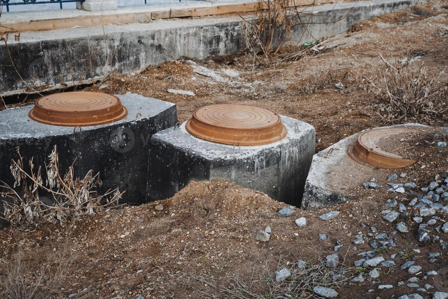 A group of concrete septic tanks is sitting in the dirt, waiting for installation. These tanks serve as an essential building material for waste management in various constructions photo