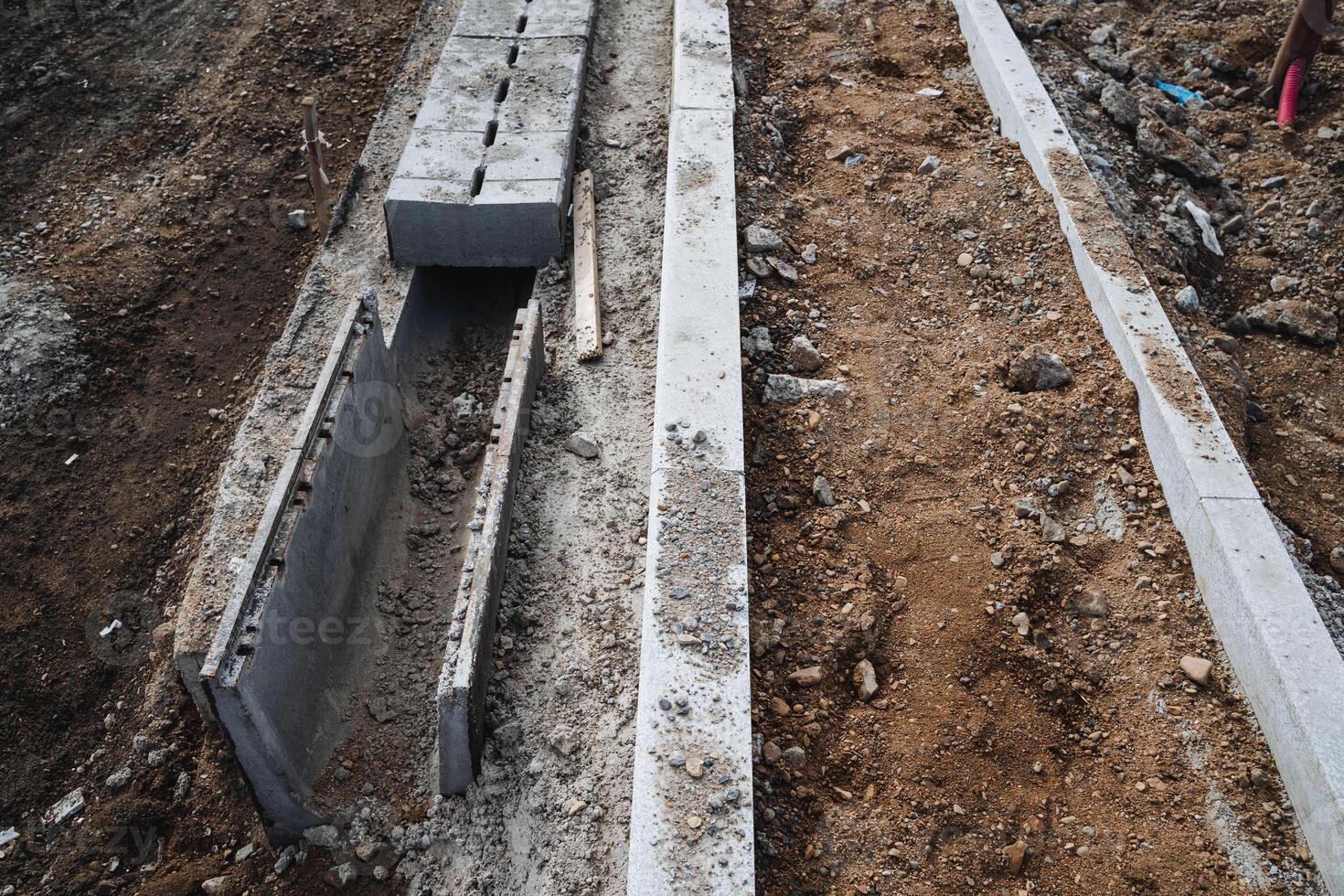 A concrete drain is currently being constructed along the side of a busy road to effectively manage water flow and drainage, ensuring proper infrastructure maintenance and efficiency photo