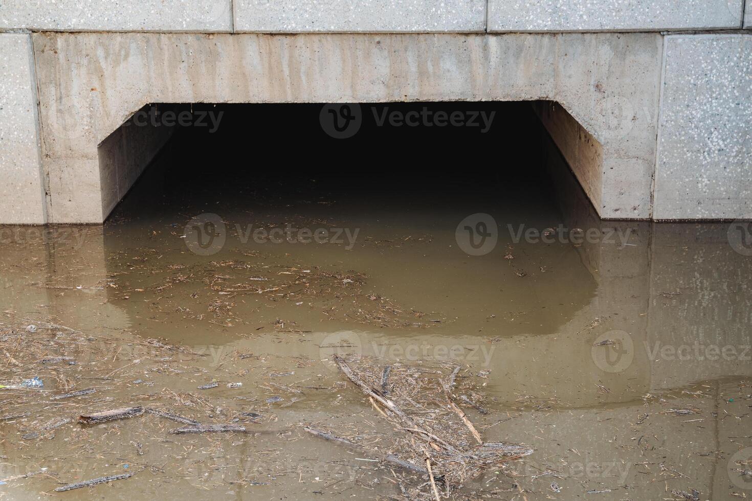 Beneath a bridge lies a significant concrete tunnel that is entirely filled with water, resulting in a fascinating landscape that is visually captivating and draws attention from onlookers photo