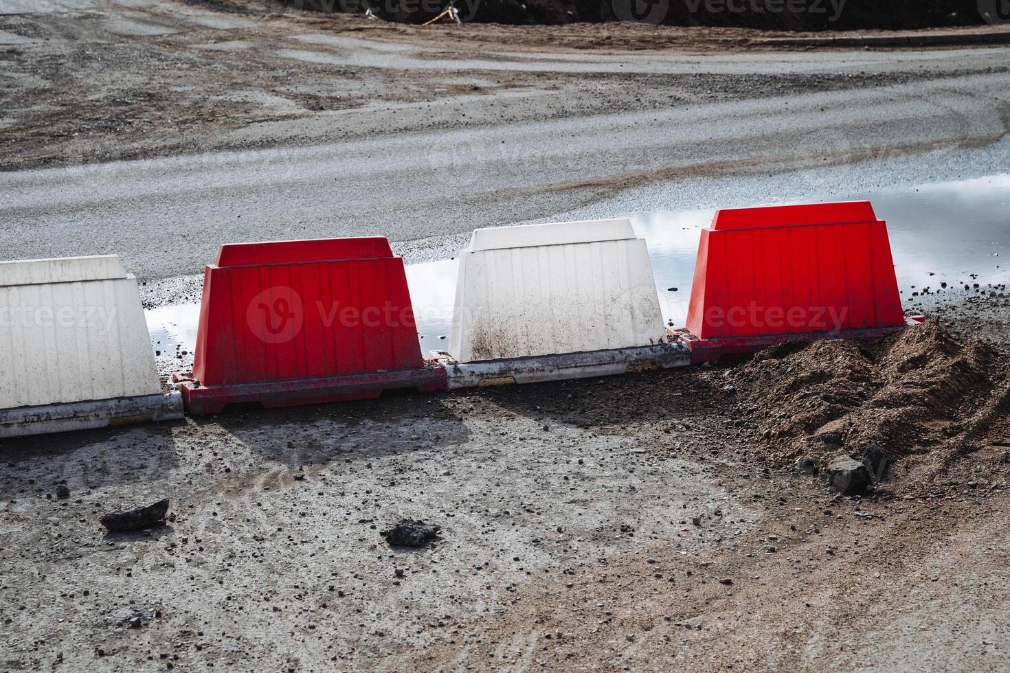 A row of red and white barriers on the side of a road photo