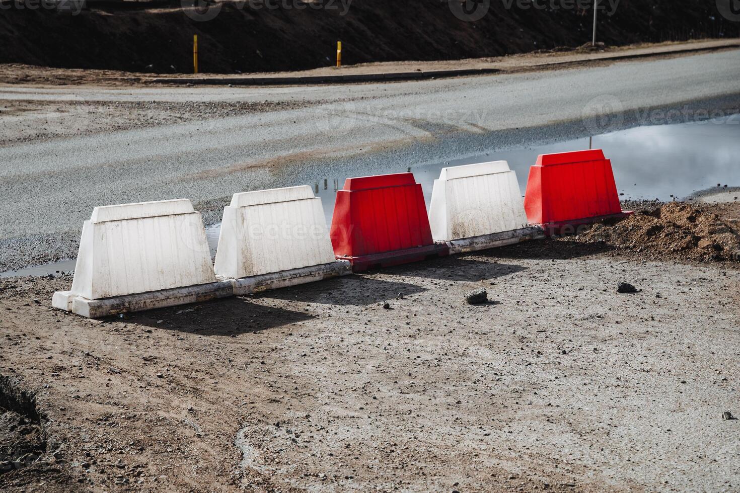 A distinct and noticeable row of red and white barriers positioned strategically on the side of a busy road, ensuring safety and guiding traffic effectively along the highway photo