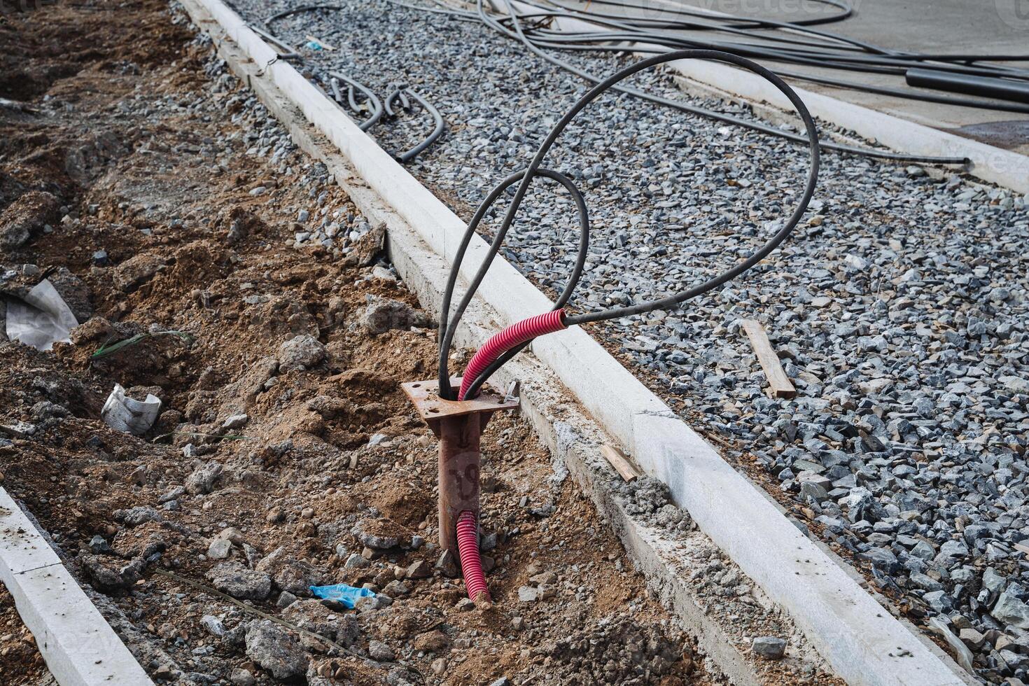 A bunch of various wires are protruding from the ground, jumbled together and creating an interesting yet chaotic sight. They appear to be part of an installation or project nearby photo