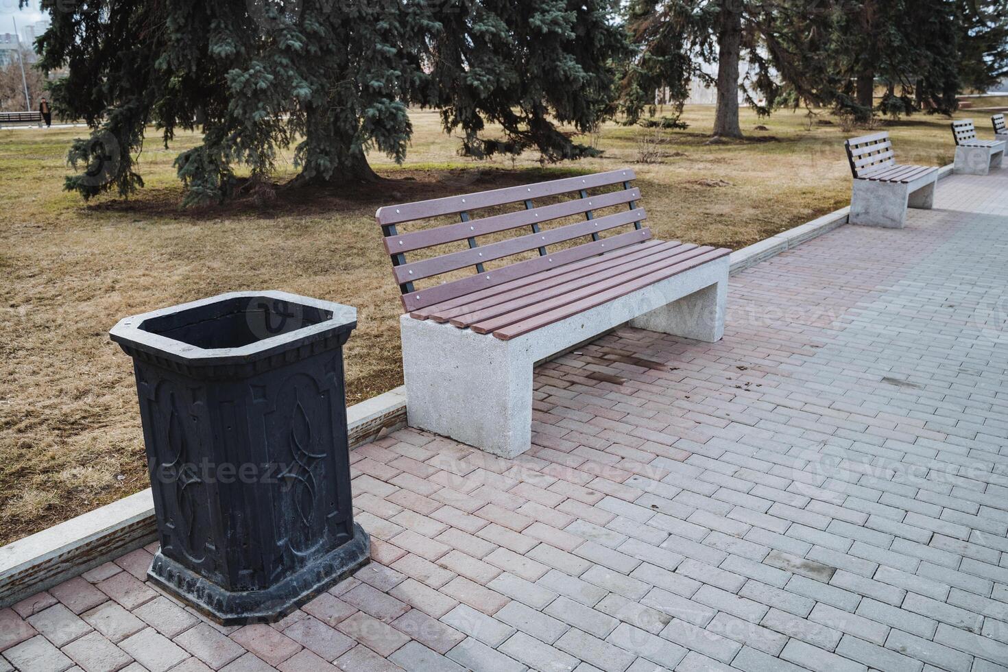 There is a lovely park that features a comfortable bench for sitting and a convenient trash can for disposing of waste, making it an inviting public space for visitors and passersby photo