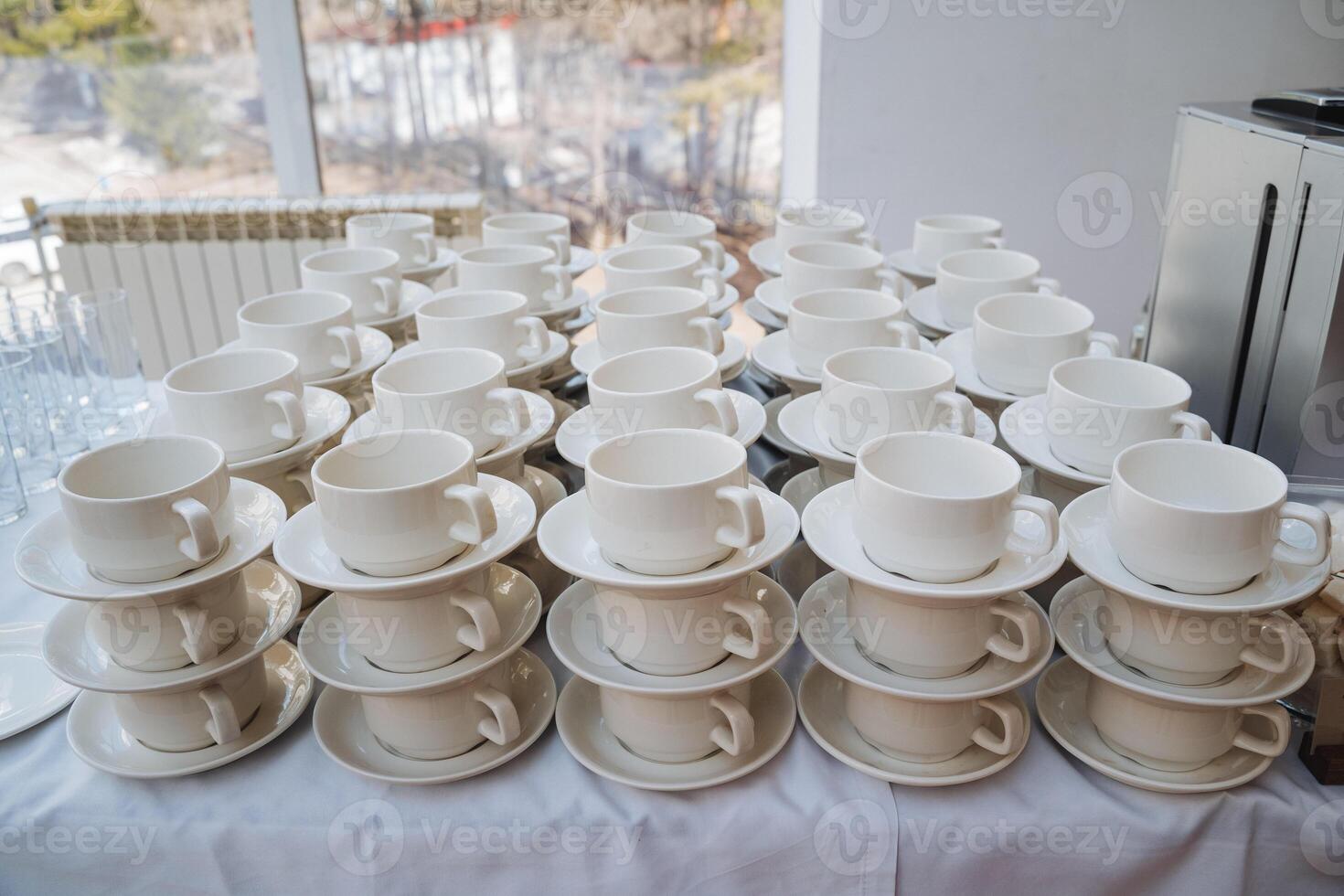 This meticulously arranged table beautifully showcases elegant white cups accompanied by matching saucers, coming together to create a chic serveware set suitable for various beverages photo