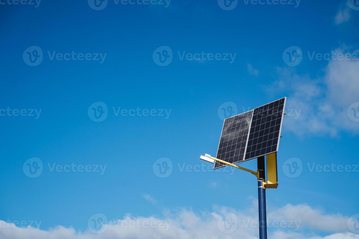 In the image, there is a solar panel mounted on a tall pole, and it is set against a vibrant blue sky that adds a beautiful contrast, emphasizing renewable energy technology photo