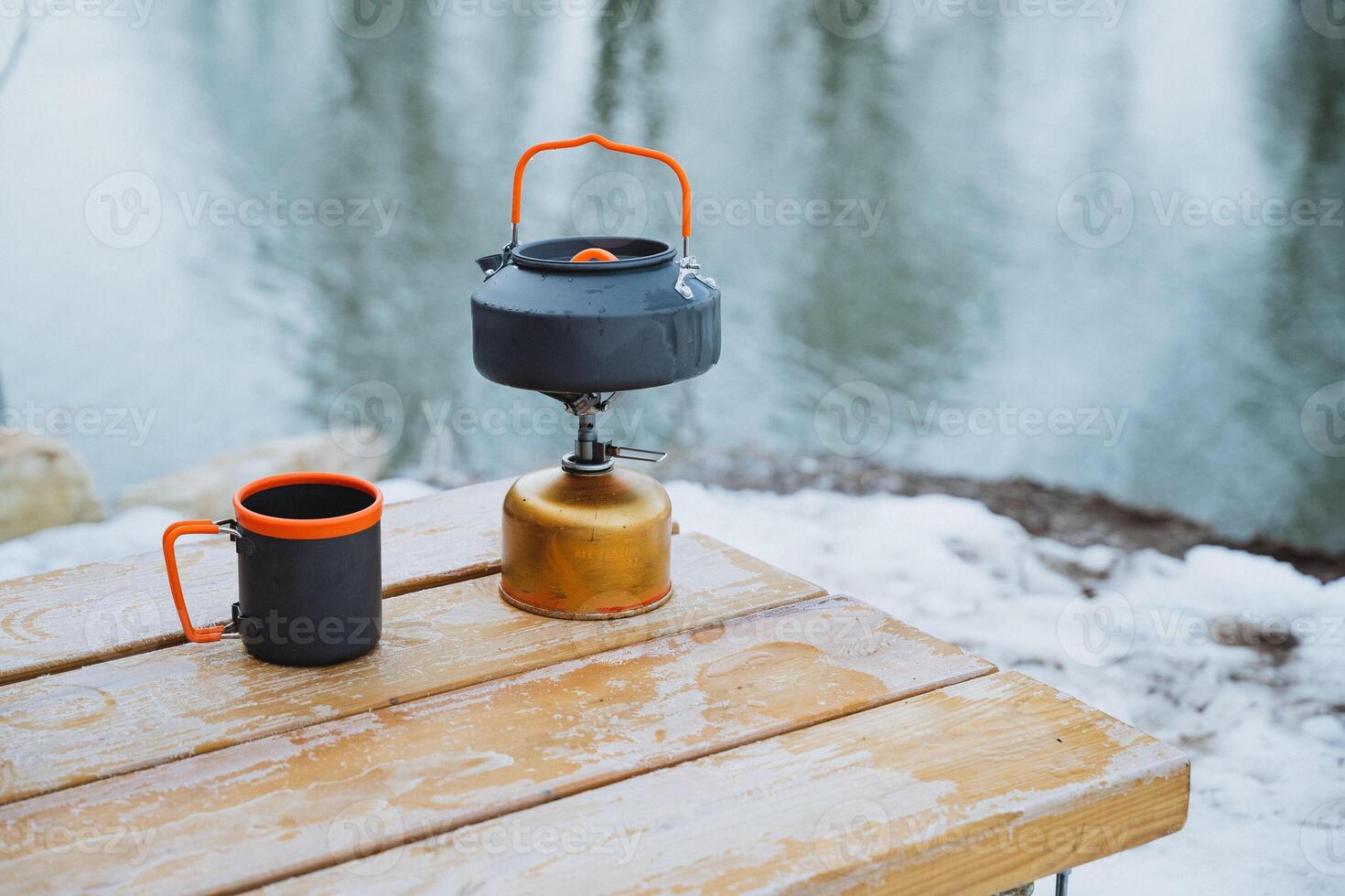 For a memorable winter camping trip, pack a portable stove and durable mugs. Enjoy warm drinks and quality time with friends by a frozen lake in natures beauty photo