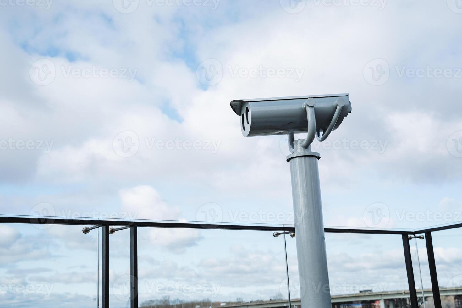 A telescope is currently positioned on top of a tall pole located on a balcony, likely meant for observation purposes. It provides a clear view over the surrounding area photo